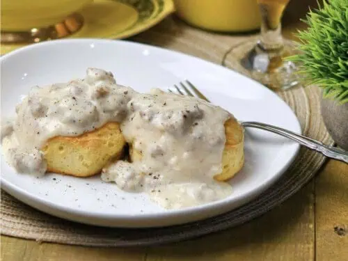 sausage gravy over biscuits on a plate, with a fork.